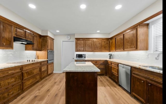 kitchen featuring stainless steel appliances, a center island, sink, and light wood-type flooring