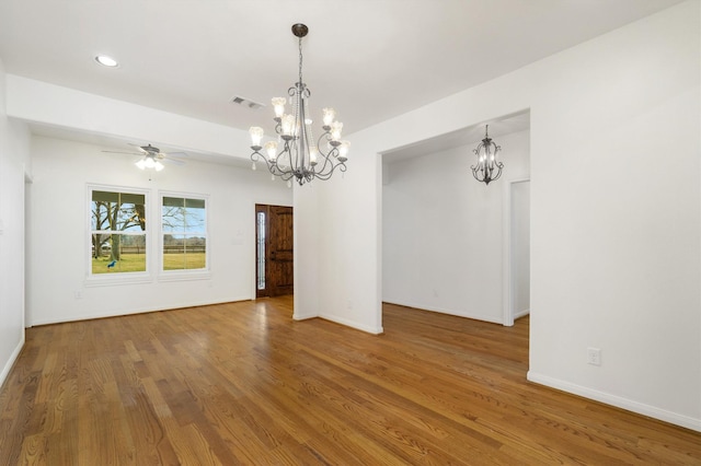 unfurnished room with ceiling fan with notable chandelier and hardwood / wood-style floors