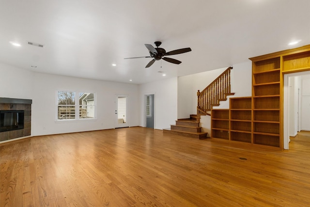 unfurnished living room featuring ceiling fan, a tile fireplace, and light hardwood / wood-style flooring