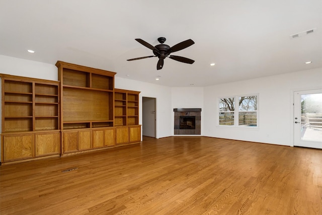 unfurnished living room featuring ceiling fan, a fireplace, and light hardwood / wood-style flooring