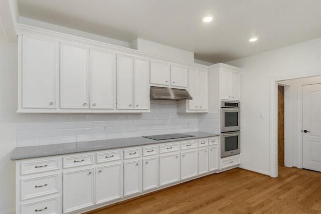 kitchen featuring white cabinetry, double oven, light stone counters, tasteful backsplash, and light hardwood / wood-style floors