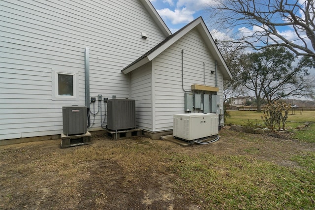 rear view of property with central AC unit and a lawn