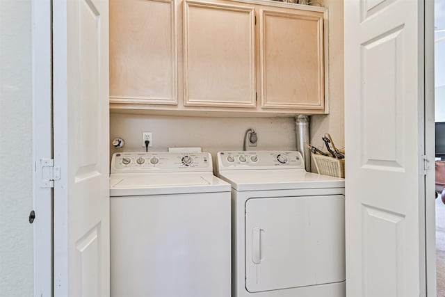 clothes washing area with cabinets and washing machine and clothes dryer