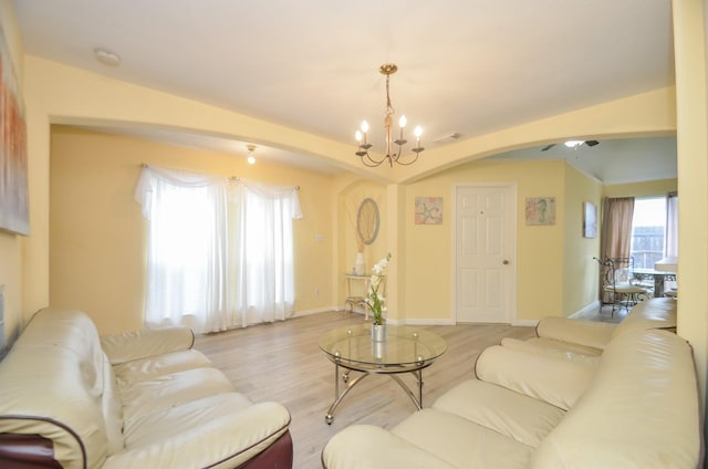 living room with ceiling fan with notable chandelier and light wood-type flooring