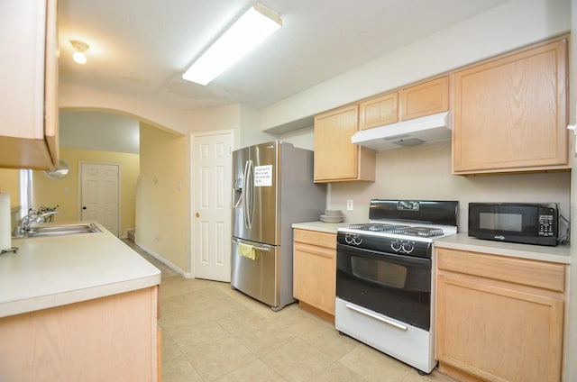 kitchen with sink, range, light brown cabinetry, and stainless steel fridge with ice dispenser