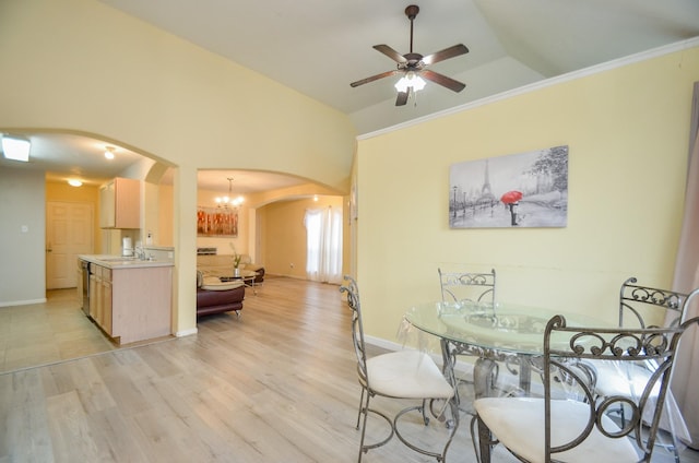 dining area with ceiling fan with notable chandelier, lofted ceiling, sink, and light hardwood / wood-style floors