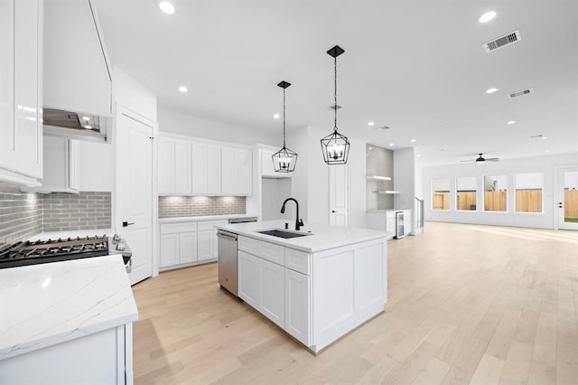 kitchen with white cabinetry, sink, pendant lighting, and an island with sink