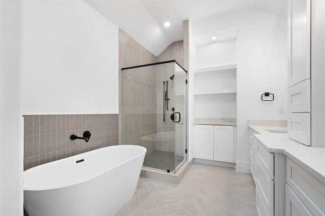 bathroom with shower with separate bathtub, vaulted ceiling, tile walls, and vanity