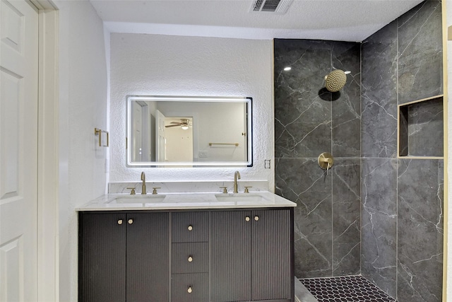 bathroom with a tile shower and vanity