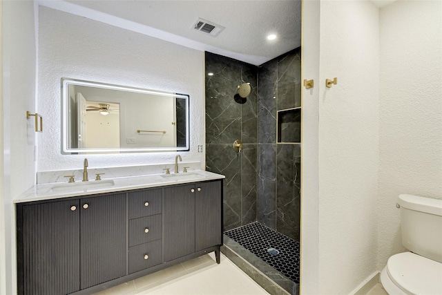 bathroom featuring vanity, toilet, and a tile shower