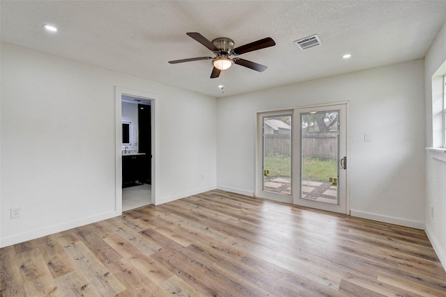 spare room featuring ceiling fan, light hardwood / wood-style floors, and a textured ceiling