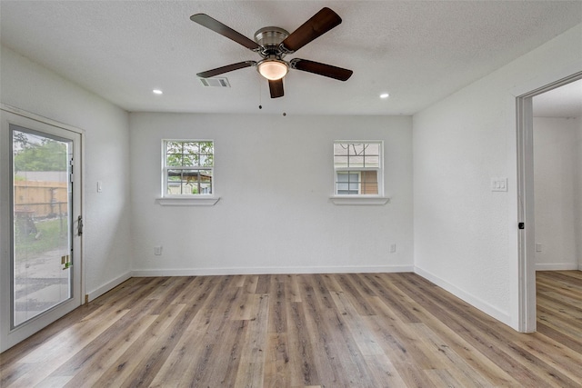 spare room with ceiling fan, a textured ceiling, and light wood-type flooring