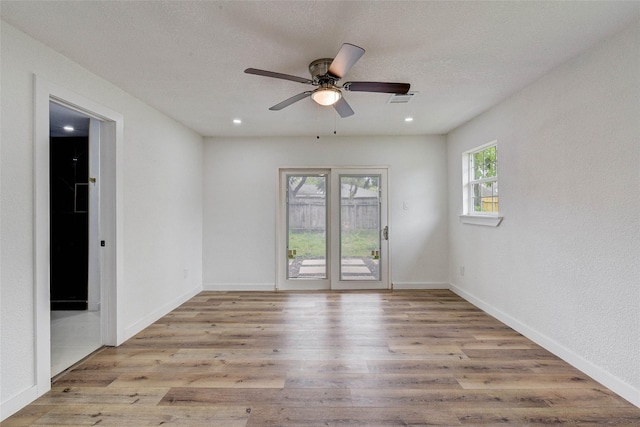 spare room with a textured ceiling, ceiling fan, and light wood-type flooring