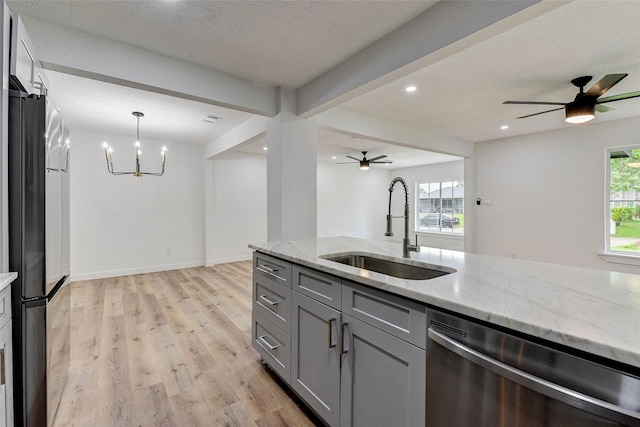 kitchen with gray cabinets, appliances with stainless steel finishes, sink, hanging light fixtures, and light stone countertops