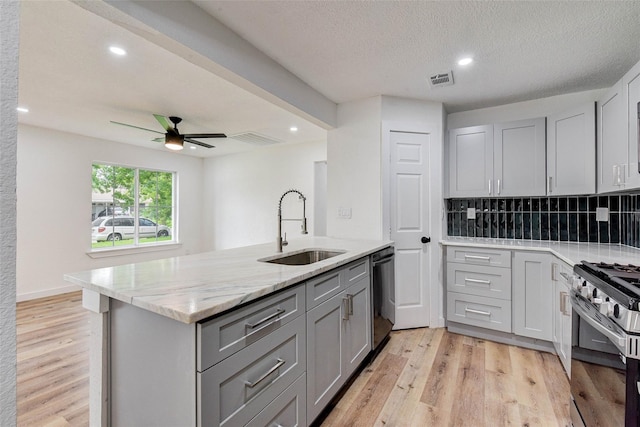 kitchen featuring gray cabinets, dishwasher, sink, gas range, and light hardwood / wood-style flooring