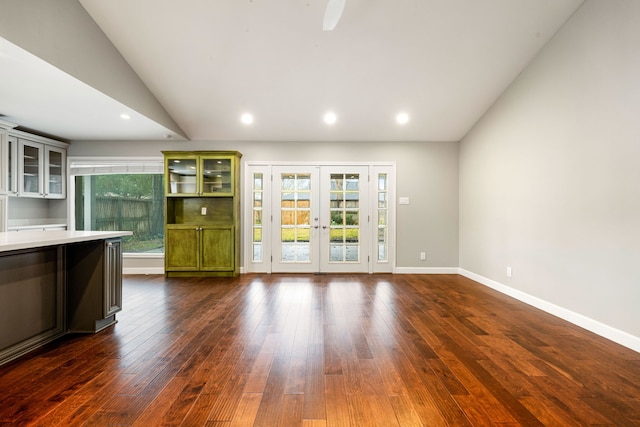 unfurnished living room featuring vaulted ceiling, dark wood-type flooring, and french doors