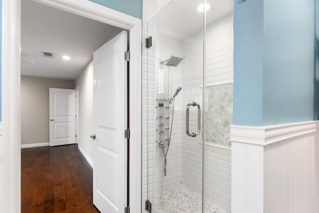 bathroom with a stall shower, wainscoting, visible vents, and wood finished floors