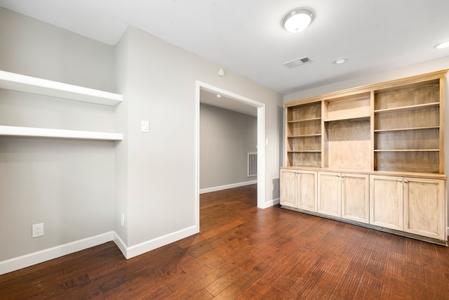 empty room featuring baseboards, visible vents, and dark wood-type flooring