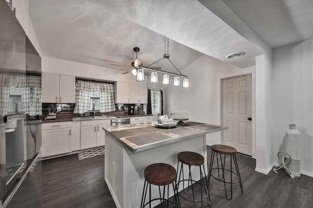 kitchen featuring pendant lighting, sink, a breakfast bar area, dark hardwood / wood-style floors, and white cabinets