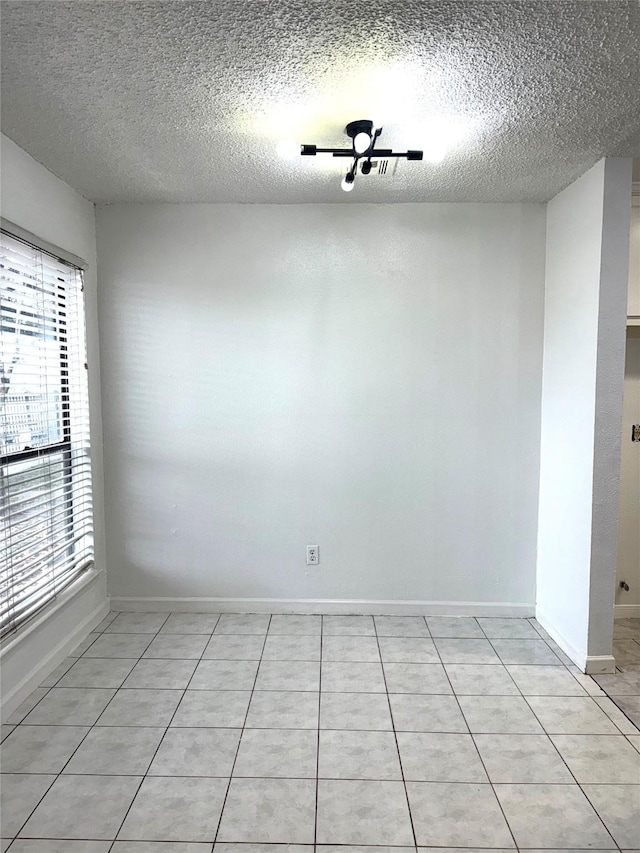 empty room with light tile patterned floors and a textured ceiling