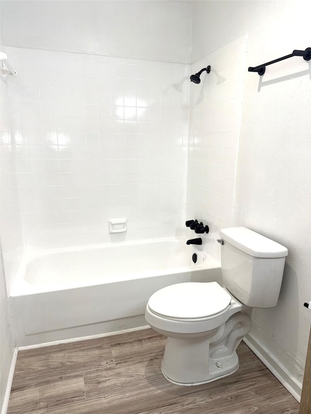 bathroom with hardwood / wood-style flooring, toilet, and tiled shower / bath combo