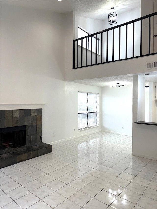 unfurnished living room featuring a high ceiling, light tile patterned flooring, a textured ceiling, and a fireplace