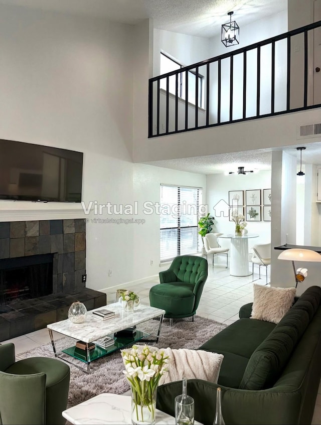 tiled living room with a high ceiling, a tile fireplace, and a textured ceiling