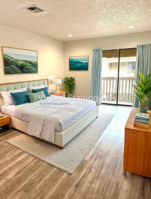 bedroom featuring hardwood / wood-style floors, access to exterior, and a textured ceiling