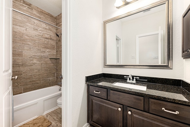 full bathroom featuring tiled shower / bath, vanity, toilet, and a textured ceiling