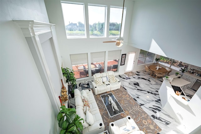 living room featuring ceiling fan and a towering ceiling