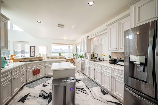 kitchen featuring sink, kitchen peninsula, a kitchen island, stainless steel appliances, and decorative backsplash