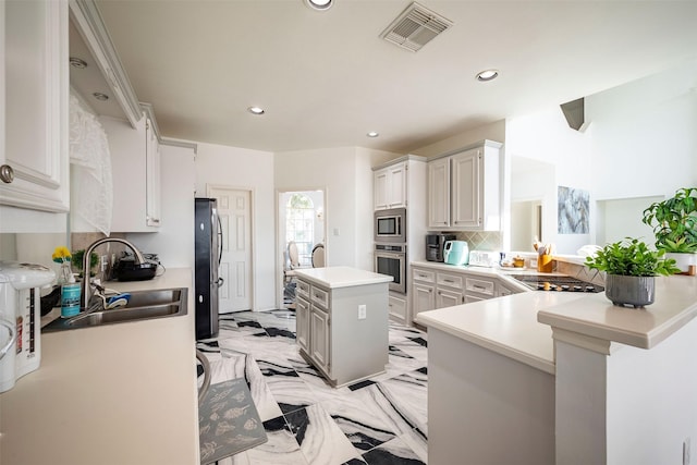 kitchen featuring sink, white cabinetry, kitchen peninsula, a kitchen island, and stainless steel appliances