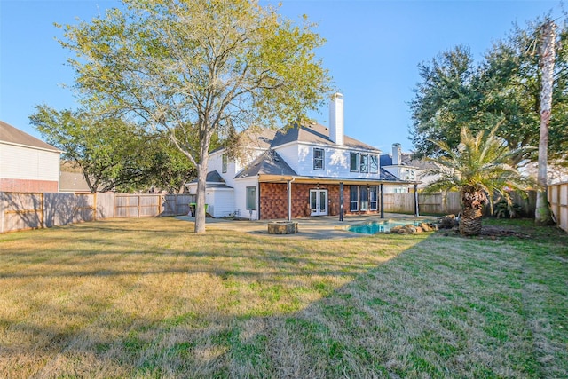 back of property featuring a yard, a patio area, and an outdoor fire pit