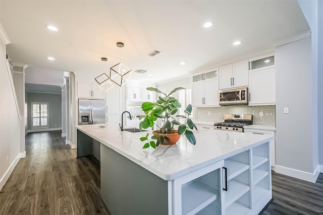 kitchen with stainless steel appliances, a center island with sink, and decorative light fixtures