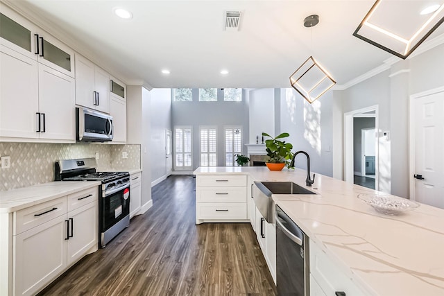 kitchen featuring appliances with stainless steel finishes, pendant lighting, sink, white cabinets, and light stone countertops