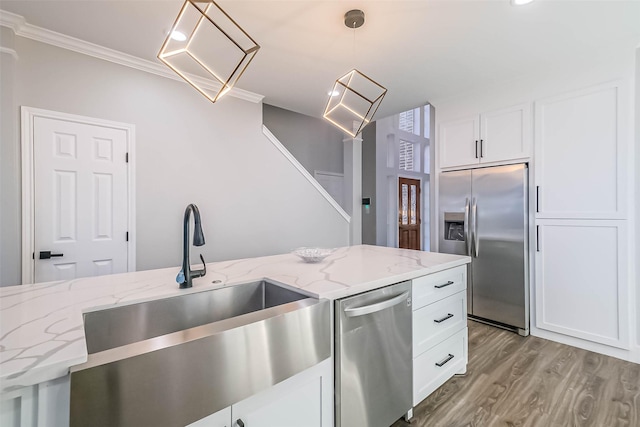 kitchen with appliances with stainless steel finishes, pendant lighting, sink, white cabinets, and light stone counters