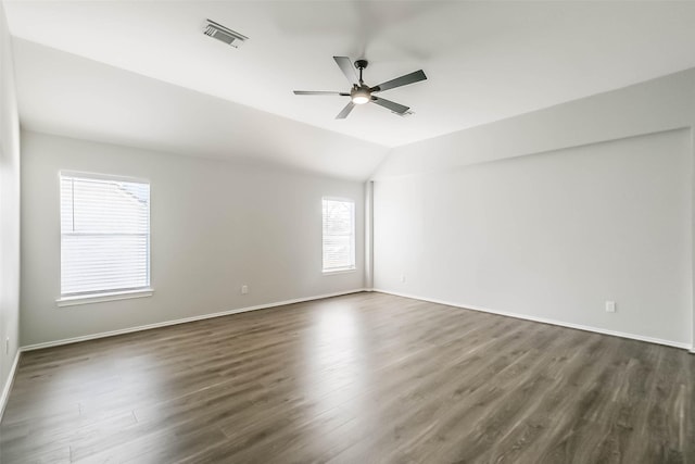 empty room featuring ceiling fan, dark hardwood / wood-style flooring, vaulted ceiling, and a wealth of natural light