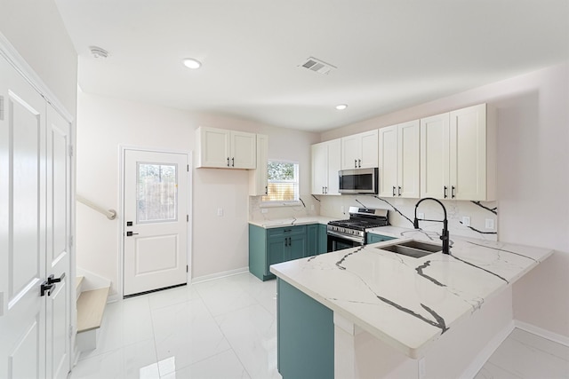 kitchen featuring appliances with stainless steel finishes, white cabinetry, sink, light stone counters, and kitchen peninsula