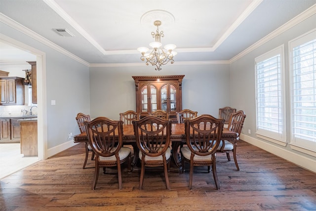 dining room with an inviting chandelier, a healthy amount of sunlight, and a tray ceiling