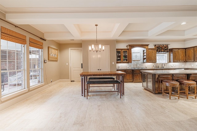 kitchen featuring tasteful backsplash, coffered ceiling, a kitchen breakfast bar, and a notable chandelier