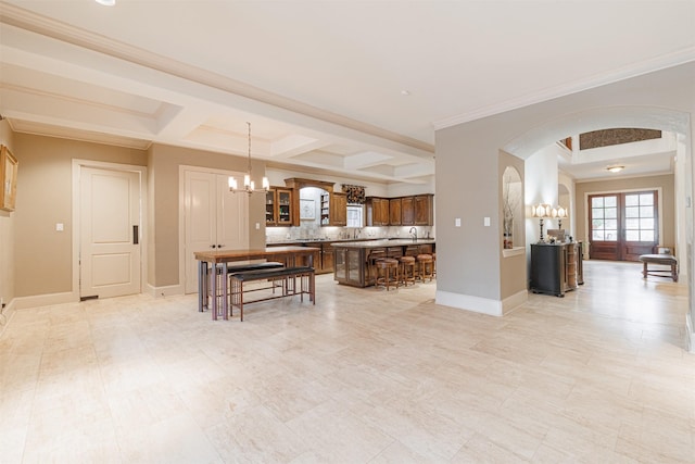 kitchen with backsplash, a kitchen bar, hanging light fixtures, coffered ceiling, and an inviting chandelier