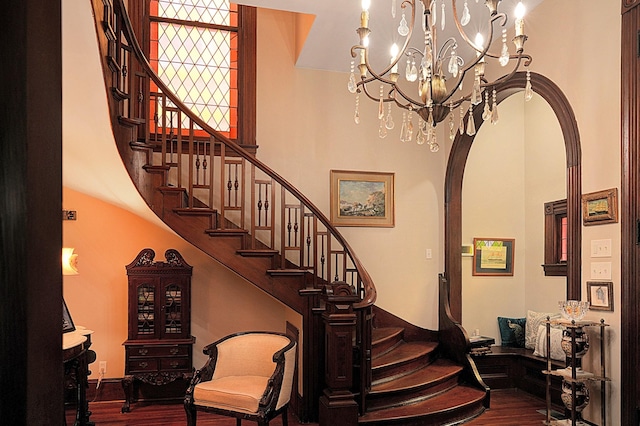 stairway with an inviting chandelier, hardwood / wood-style floors, and a high ceiling