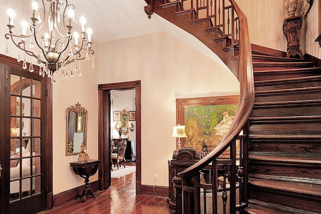 staircase featuring hardwood / wood-style flooring and an inviting chandelier