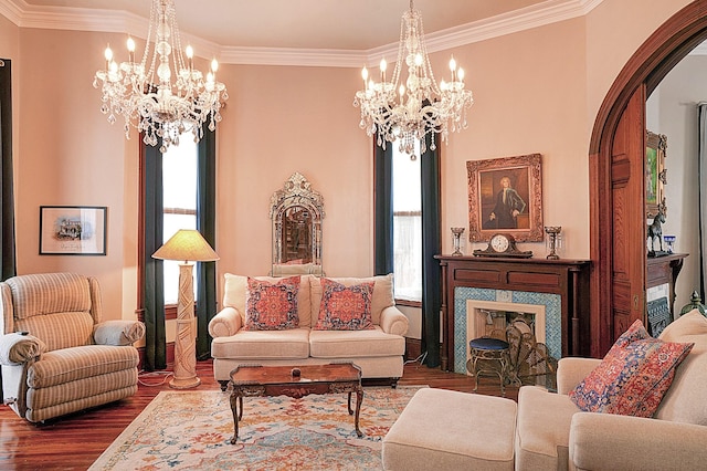 living room featuring an inviting chandelier, hardwood / wood-style floors, crown molding, and a high end fireplace