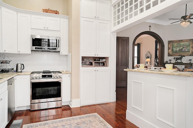 kitchen featuring white cabinetry, stainless steel appliances, tasteful backsplash, light stone countertops, and dark hardwood / wood-style flooring