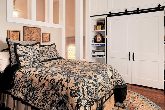 bedroom with a barn door, dark hardwood / wood-style flooring, and a closet