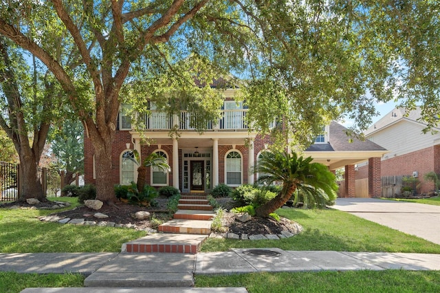 view of front of home featuring a carport, a balcony, and a front yard