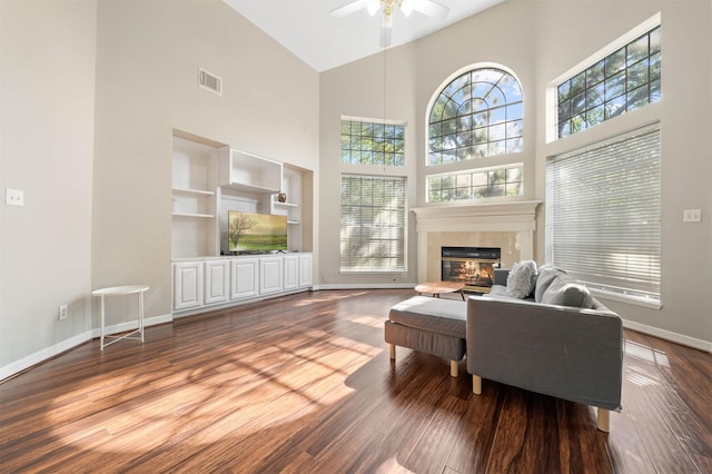 living room featuring wood-type flooring, a fireplace, high vaulted ceiling, and plenty of natural light