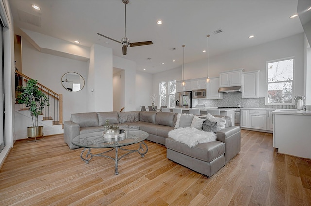 living room featuring ceiling fan, plenty of natural light, sink, and light hardwood / wood-style flooring