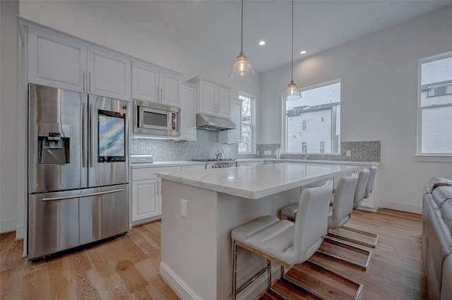 kitchen with stainless steel appliances, white cabinetry, a kitchen breakfast bar, and decorative light fixtures